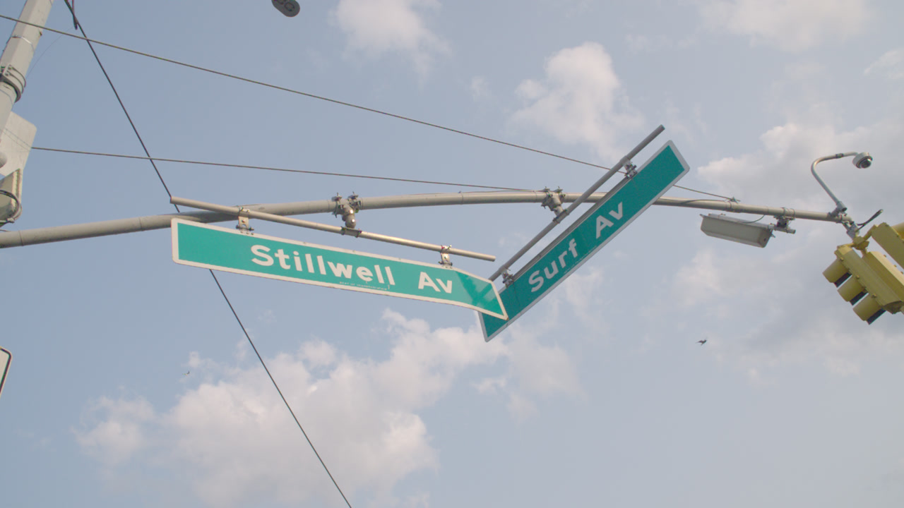 Establishing shot of street signs in Coney Island. Shot at the intersection of Stillwell Avenue and Surf Avenue in Brooklyn.