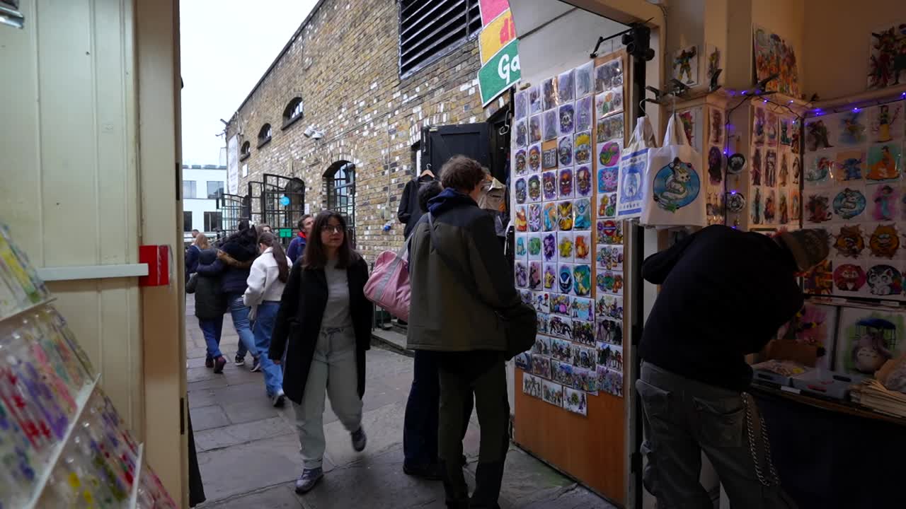 Tourists explore Camden Market in London browsing colorful souvenir stalls on a busy day