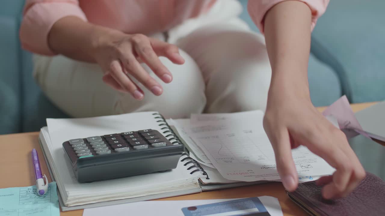 cerca de la mano de la mujer calculando dinero con una calculadora antes de abrir el bolso para comprobar el dinero