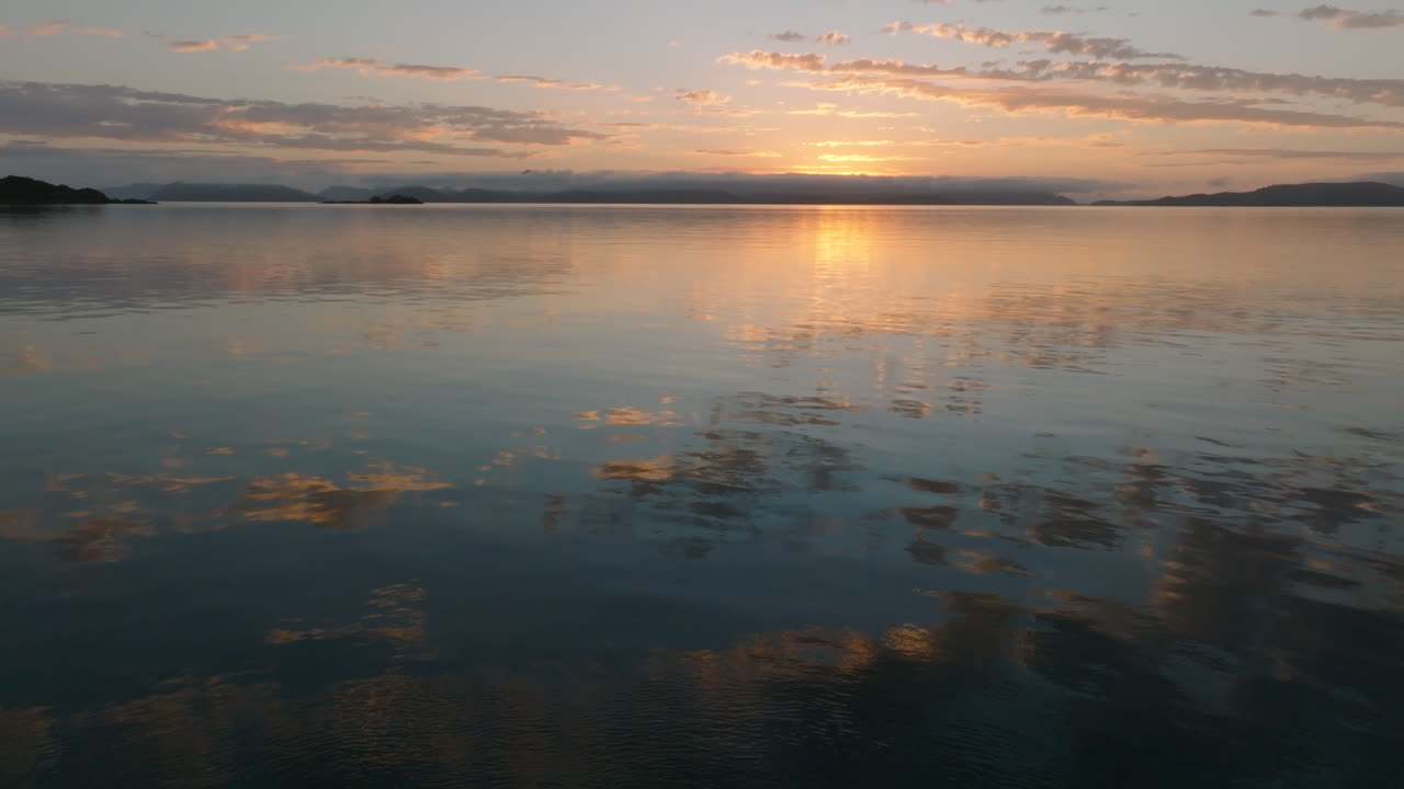 Stationary shot of the beautiful coloured sky and clouds reflecting in the still ocean waters of the Whitsunday Islands during sunrise