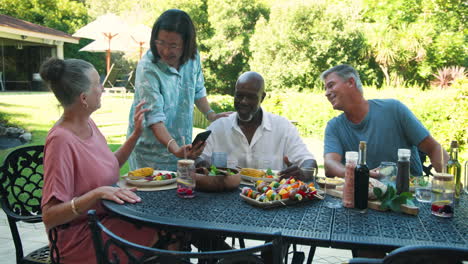 sharing laughter, diverse senior friends having in garden lunch with healthy food