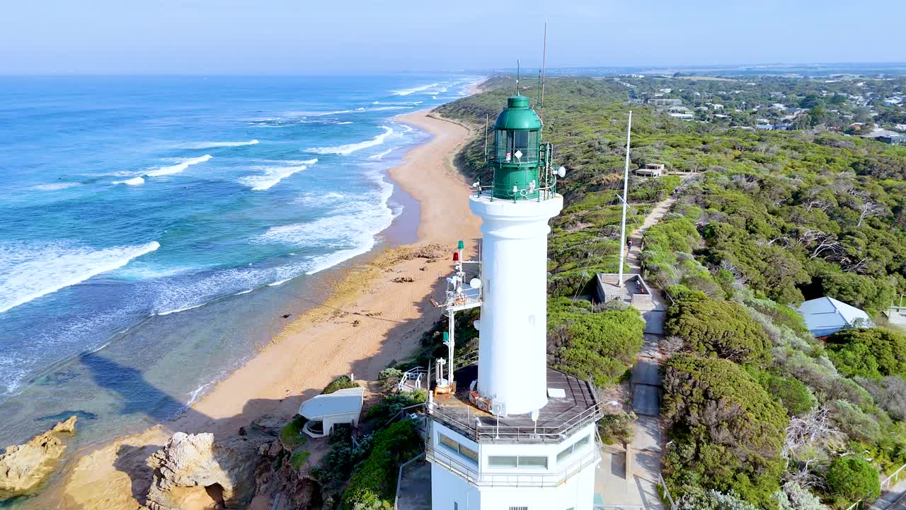 Aerial footage of Point Lonsdale Lighthouse with sweeping views of the beach and ocean under clear skies