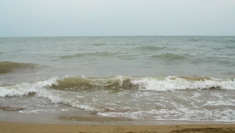small waves comes in on a sandy beach and the weather is not so fine.
