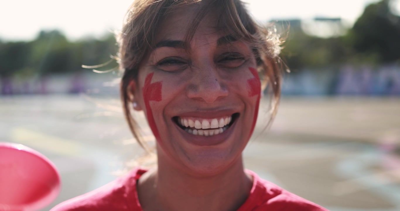 Donna felice con il viso dipinto di rosso che sorride alla telecamera
