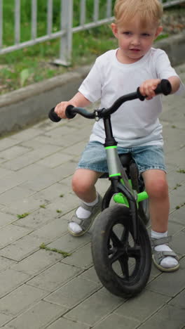 un niño monta una bicicleta alegremente, con una visión de la pierna de una mujer montando un scooter a su lado