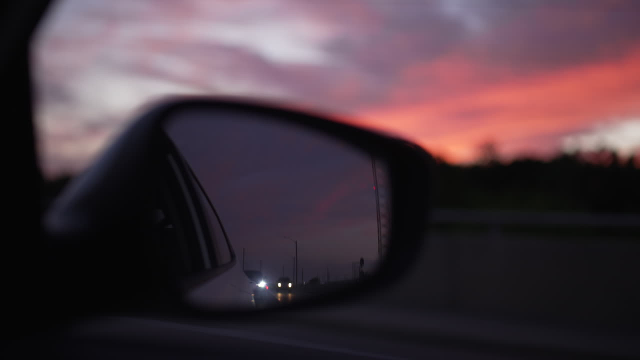 Riflesso di altri veicoli nello specchietto laterale del passeggero, durante un bellissimo tramonto all'ora d'oro