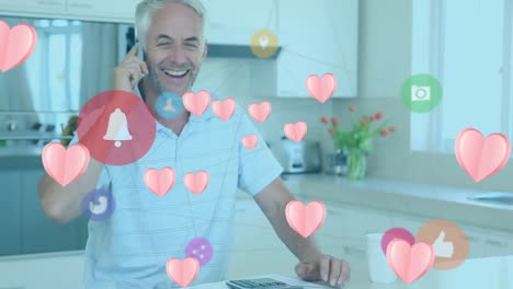 Animación-De-íconos-De-Corazón-Rosa-Y-Red-De-íconos-Digitales-Sobre-Un-Hombre-Caucásico-Hablando-Por-Teléfono-Inteligente