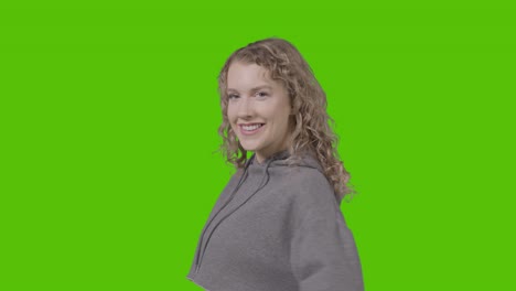 studio portrait of smiling young woman against green screen 1