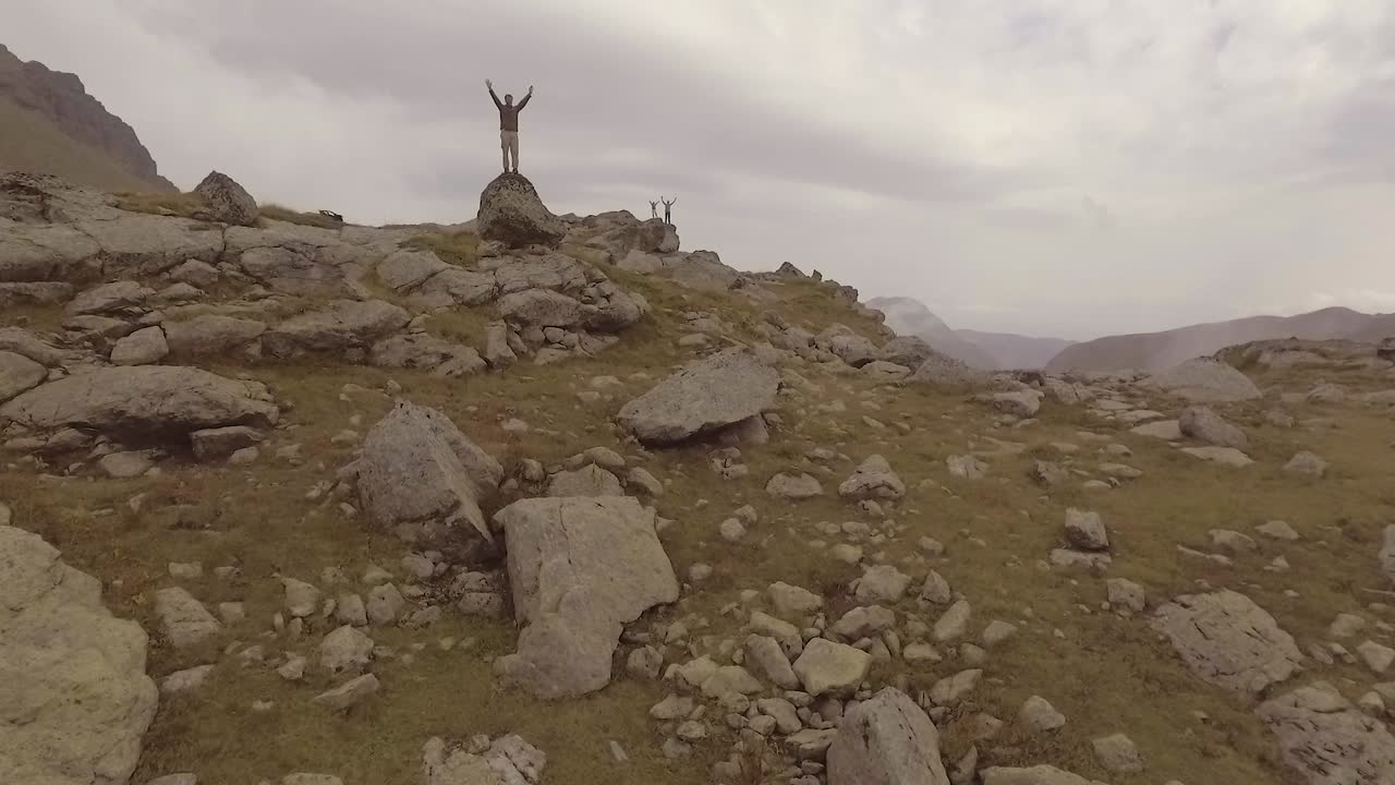 toma aérea de las montañas de kosovo con hombres parados con los brazos abiertos