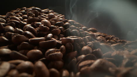 pila de granos de café tostados con humo que se eleva en cámara lenta, dolly fuera