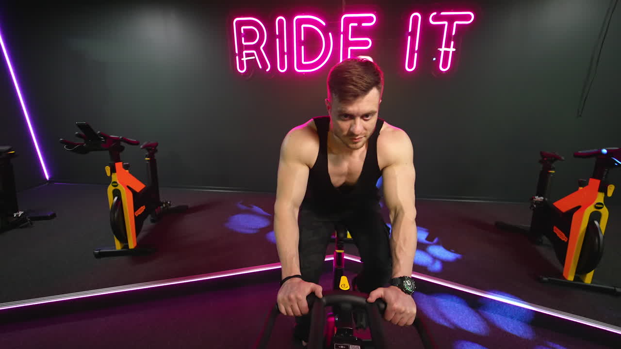 Man training on spin bike. Front view of man spin legs on smart trainer in gym