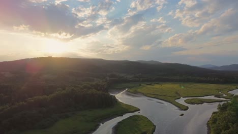 cinematic view from a drone that flies over the river that flows under the mountains among the greenery