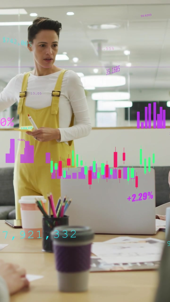 Video vertical: Mujer sosteniendo un marcador y notas, iniciando gráficos bursátiles en un portátil para negocios.