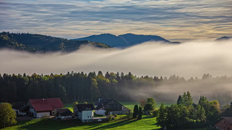 mountain forest blanketed by clouds at dawn, misty dawn atmosphere outside, sun over the village