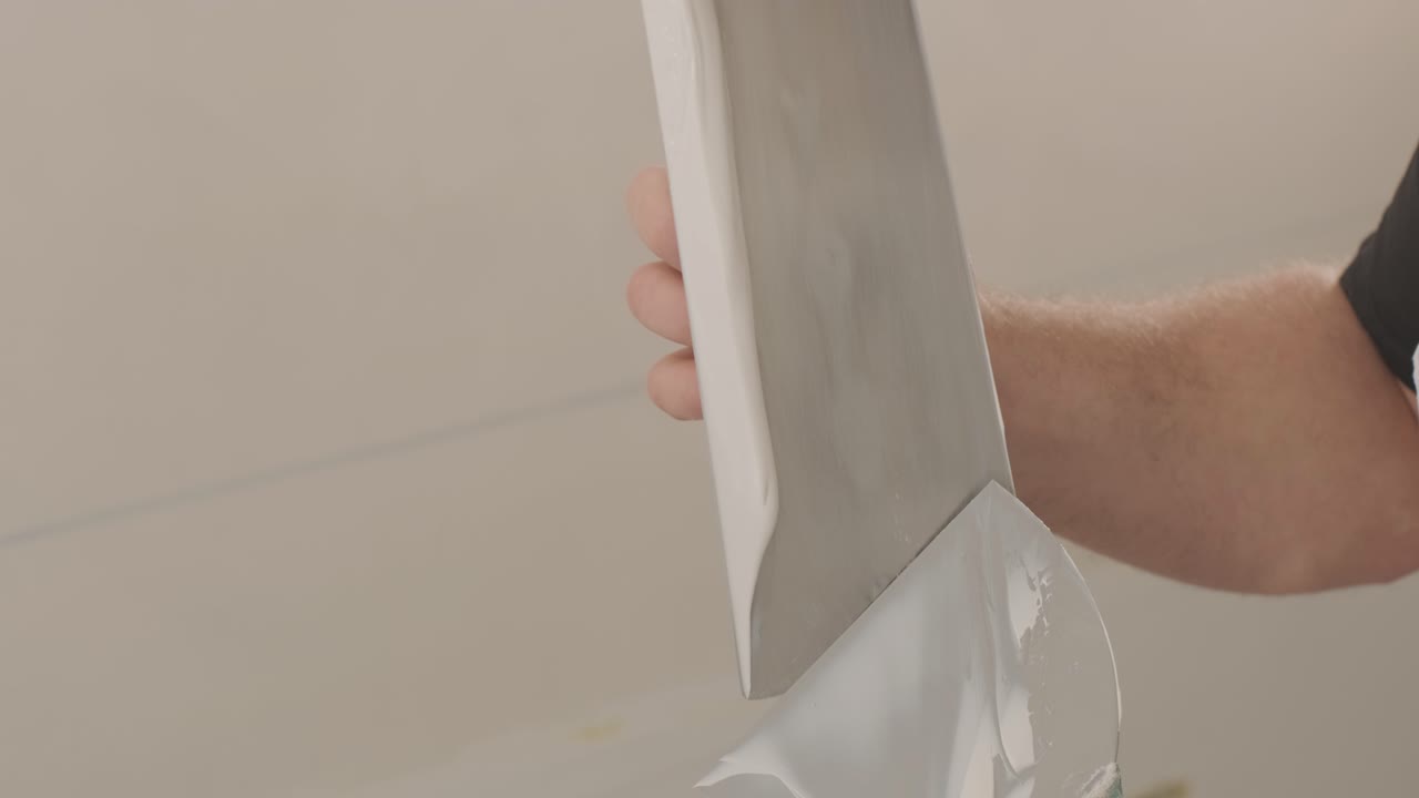 Man plastering the walls with finishing putty in room with putty spatula