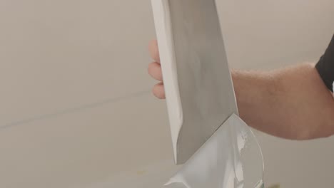 man plastering the walls with finishing putty in room with putty spatula