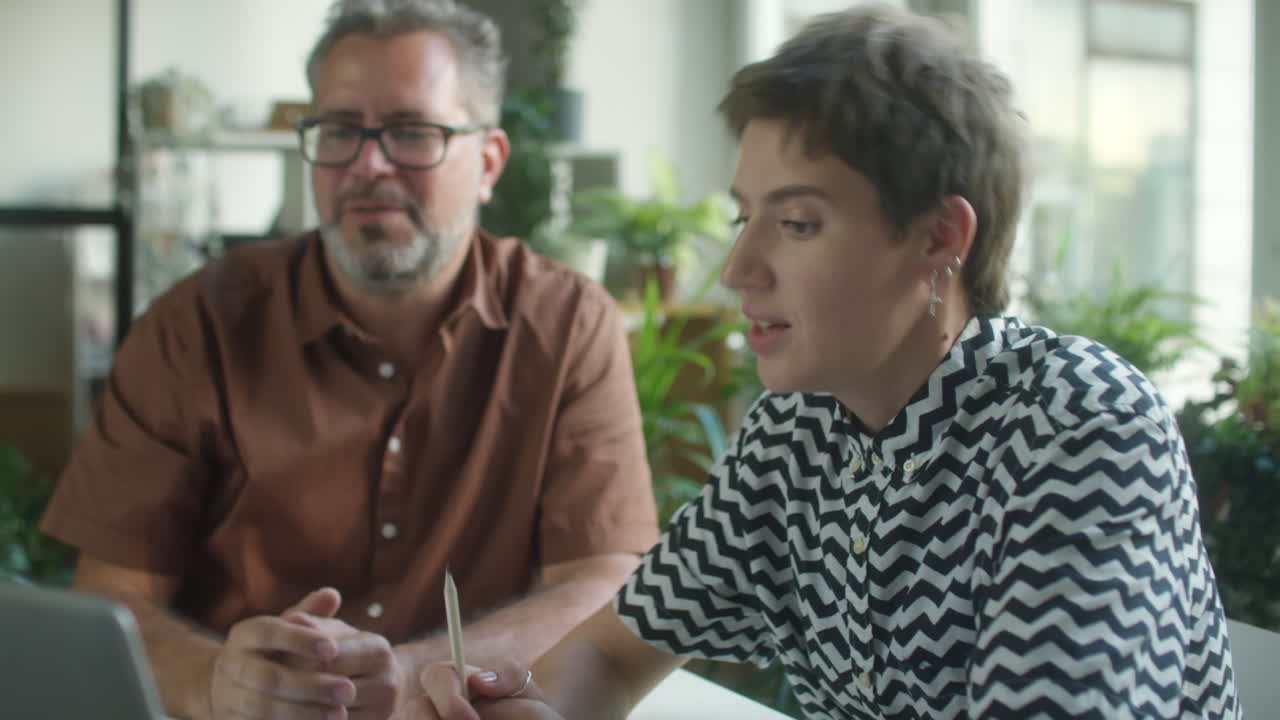 Coworkers Discussing Project on Laptop in Office