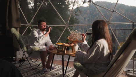 couple enjoying wine and snacks in a geodesic dome with a mountain view