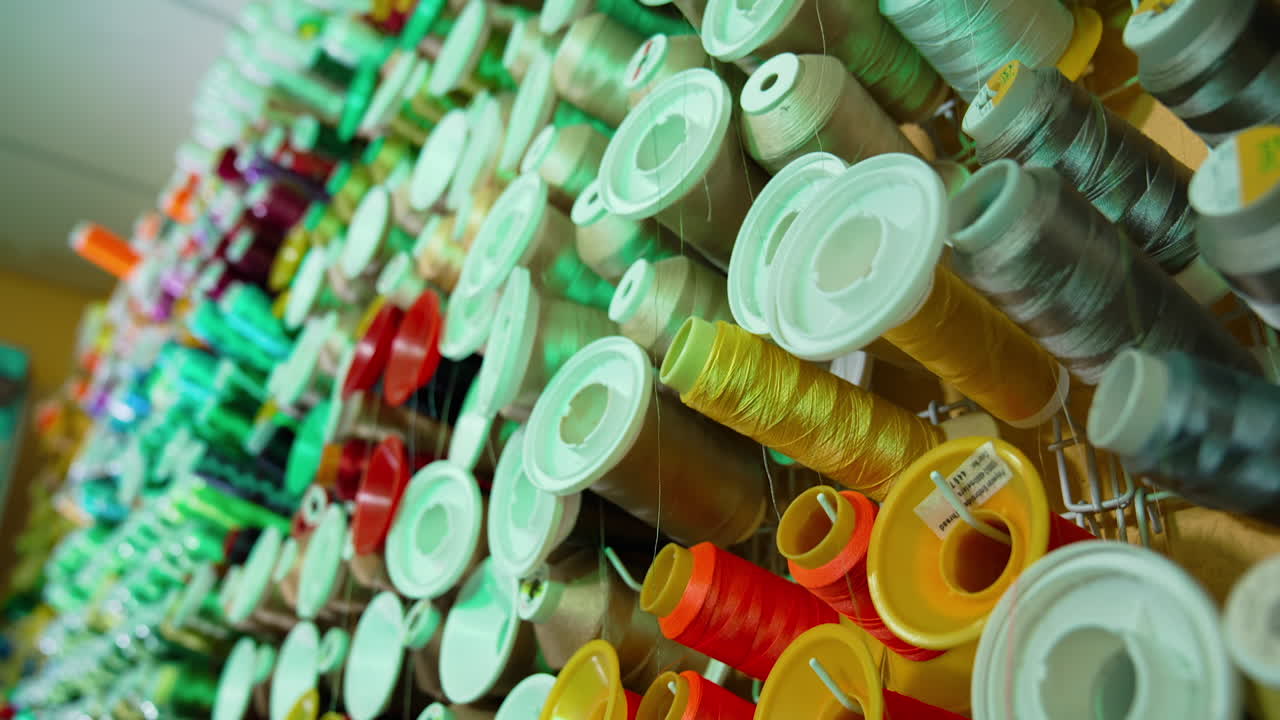 Spools of thread of different colors on the table. Collection of colorful threads for sewing industry. Background of many spools with cotton string.