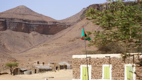 mauritania flag waving in terjit oasis village in sahara desert of africa