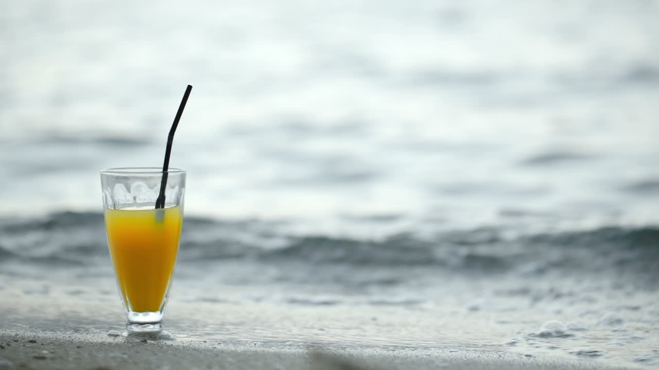 un vaso de cóctel en la playa y las olas lavando la orilla