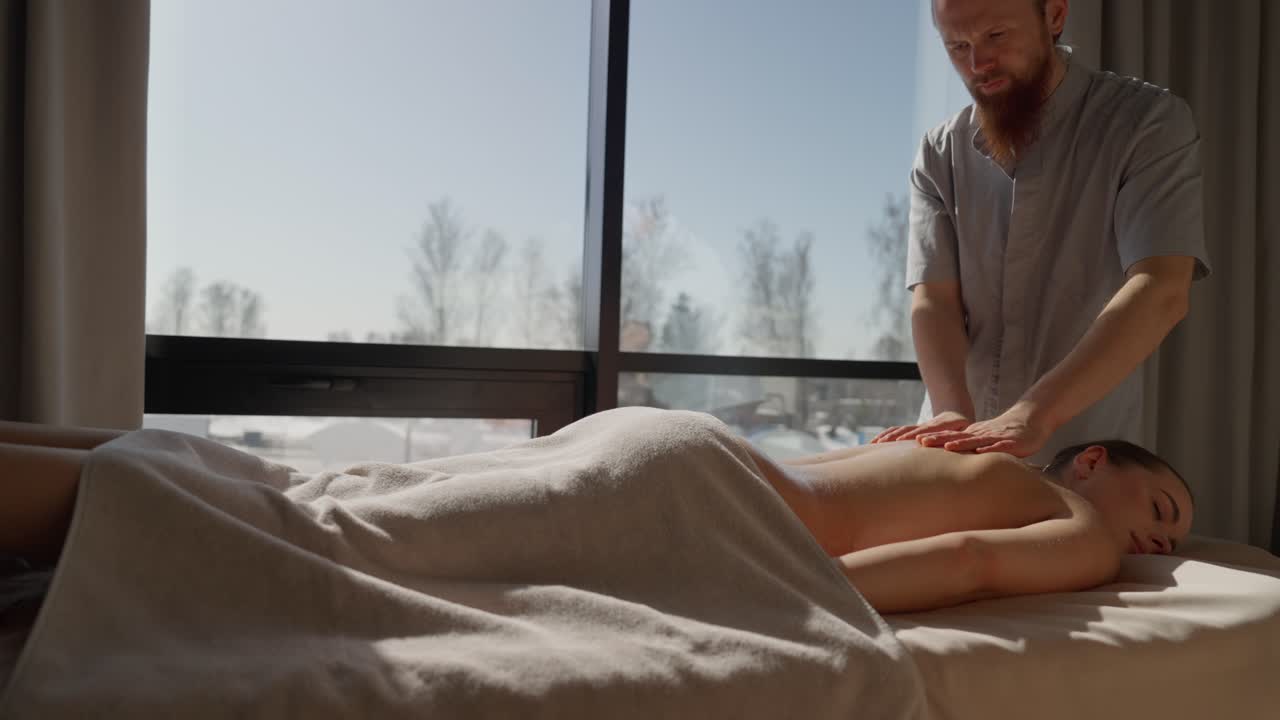 Masajista profesional dando un masaje de espalda relajante a una mujer