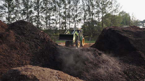 a green tractor of a farm is loading something on front loader, machinery of agriculture business, working on a sunny day