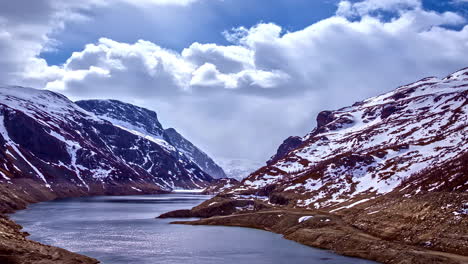 lapso de tiempo de nubes blancas en movimiento sobre el valle del río con nieve en la ladera de la montaña