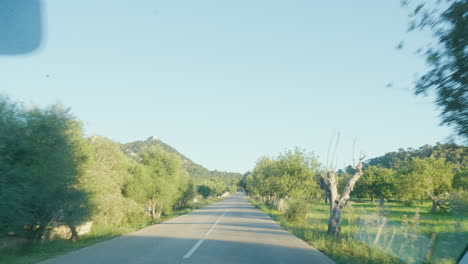 A-scenic-drive-on-a-country-road-in-Mallorca,-with-the-view-captured-from-the-car-window,-presenting-a-dynamic-perspective-of-the-journey