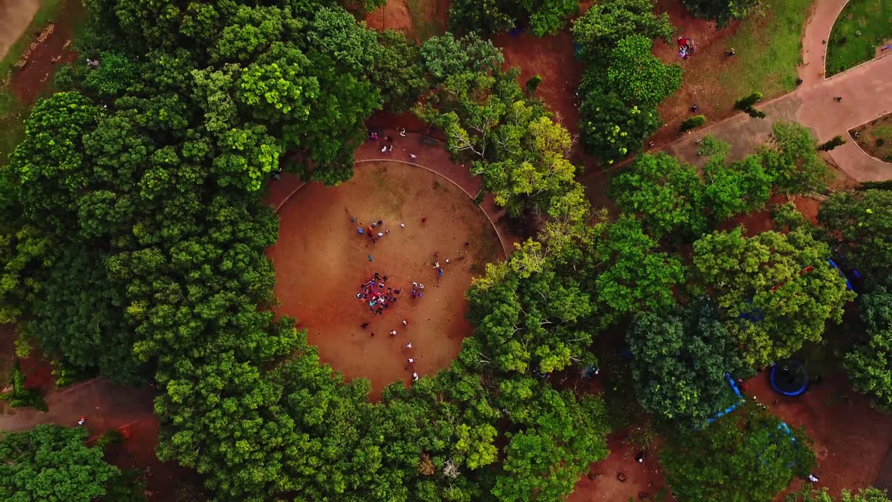 una foto aérea de una gran multitud en un lugar abierto rodeado de árboles verdes en un hermoso parque en abuja, nigeria
