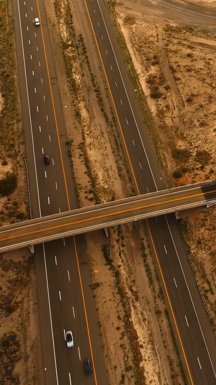 Speedways and freeways built in the desert of California. Cars driving by the roads. Aerial view. Vertical video