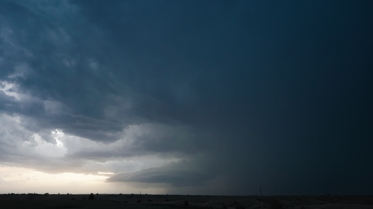 Rolling cumulonimbus cloud illuminated by constant lightning at dusk