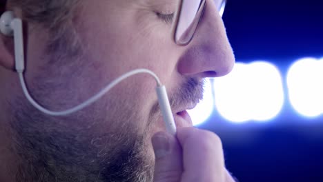 side view of bearded man with glasses talking into ios style ear bud