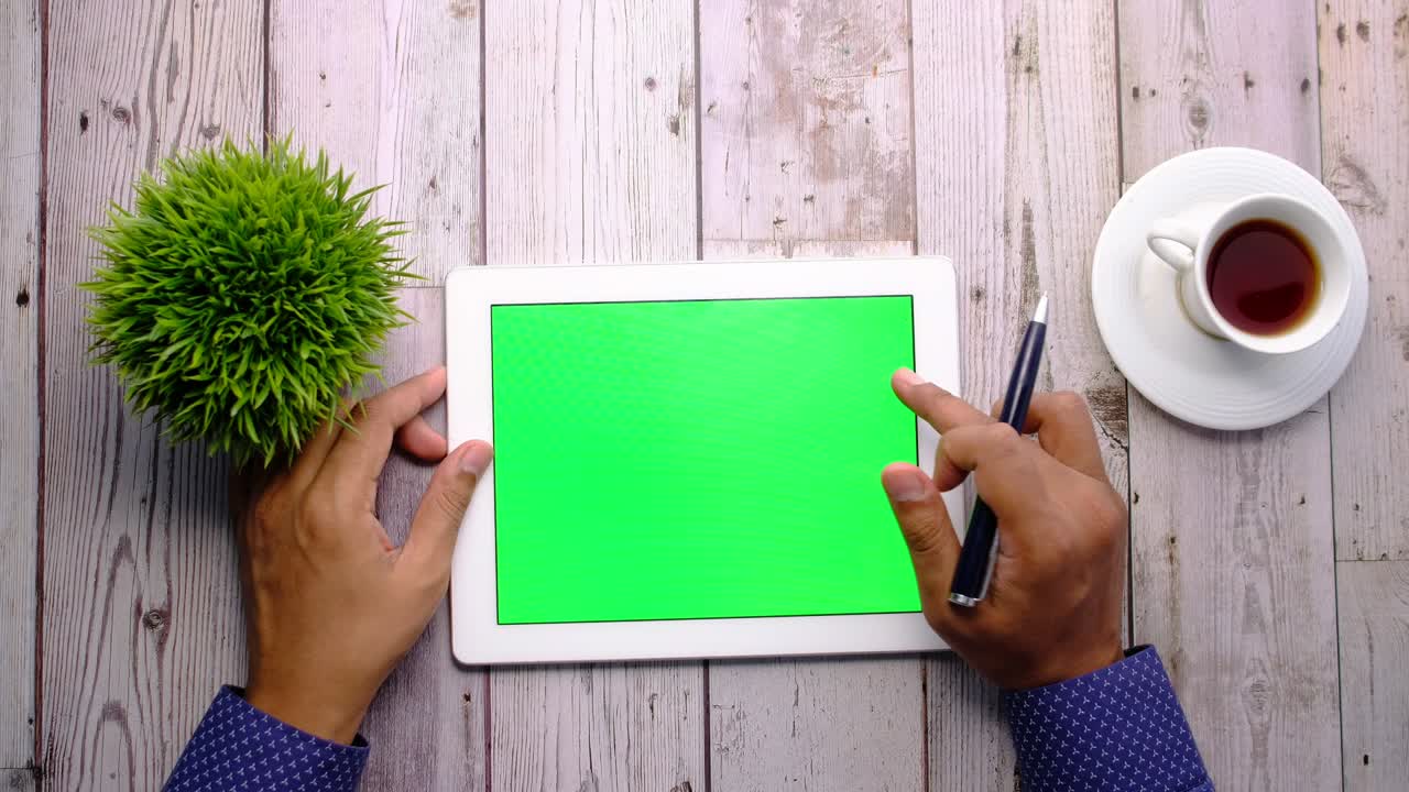 person working on digital tablet with green screen at office desk