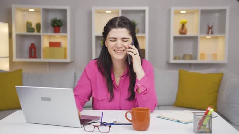 una trabajadora de oficina en casa hablando felizmente por teléfono.