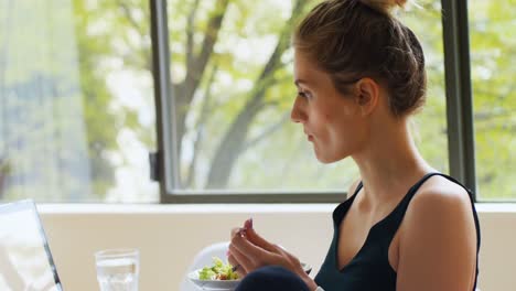 woman eating salad while using laptop 4k