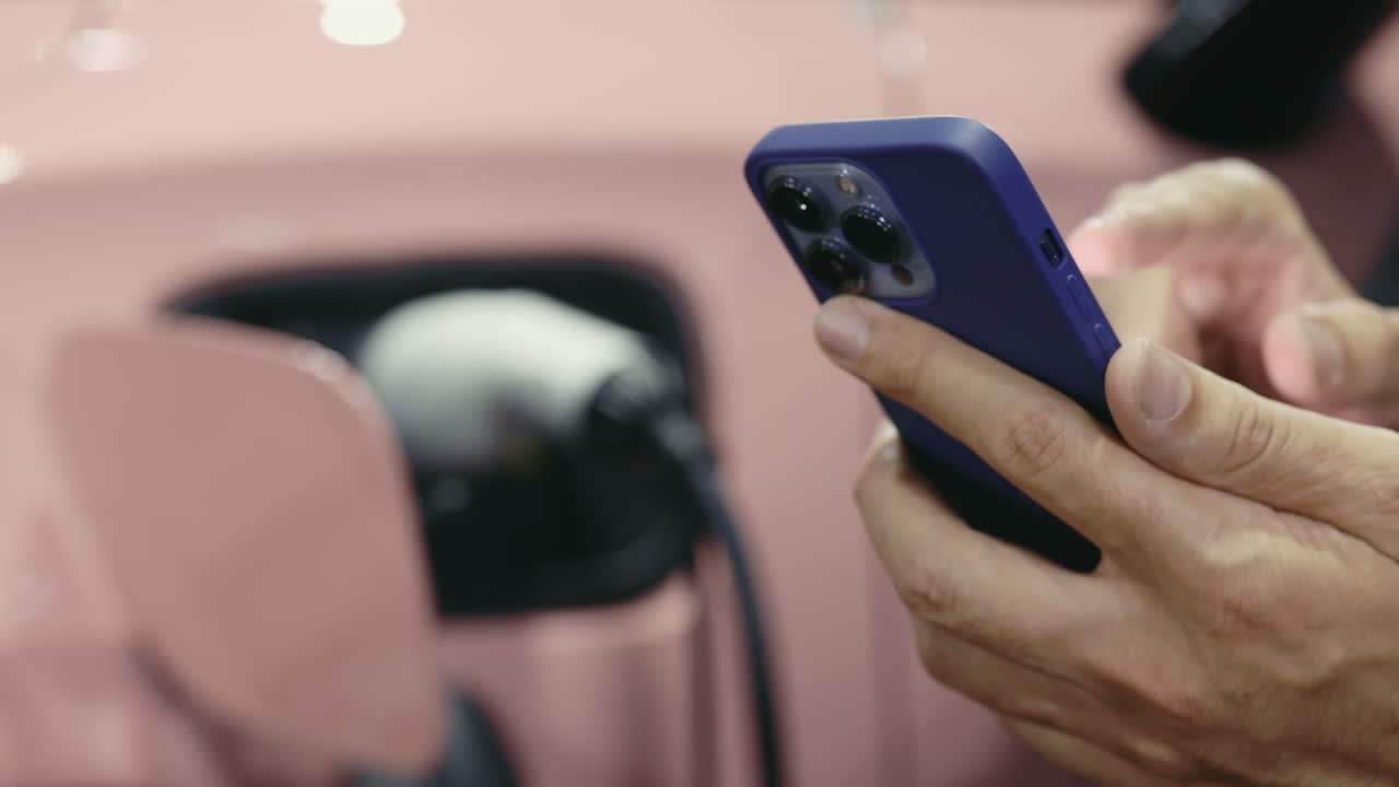 Person using smartphone while charging an electric vehicle