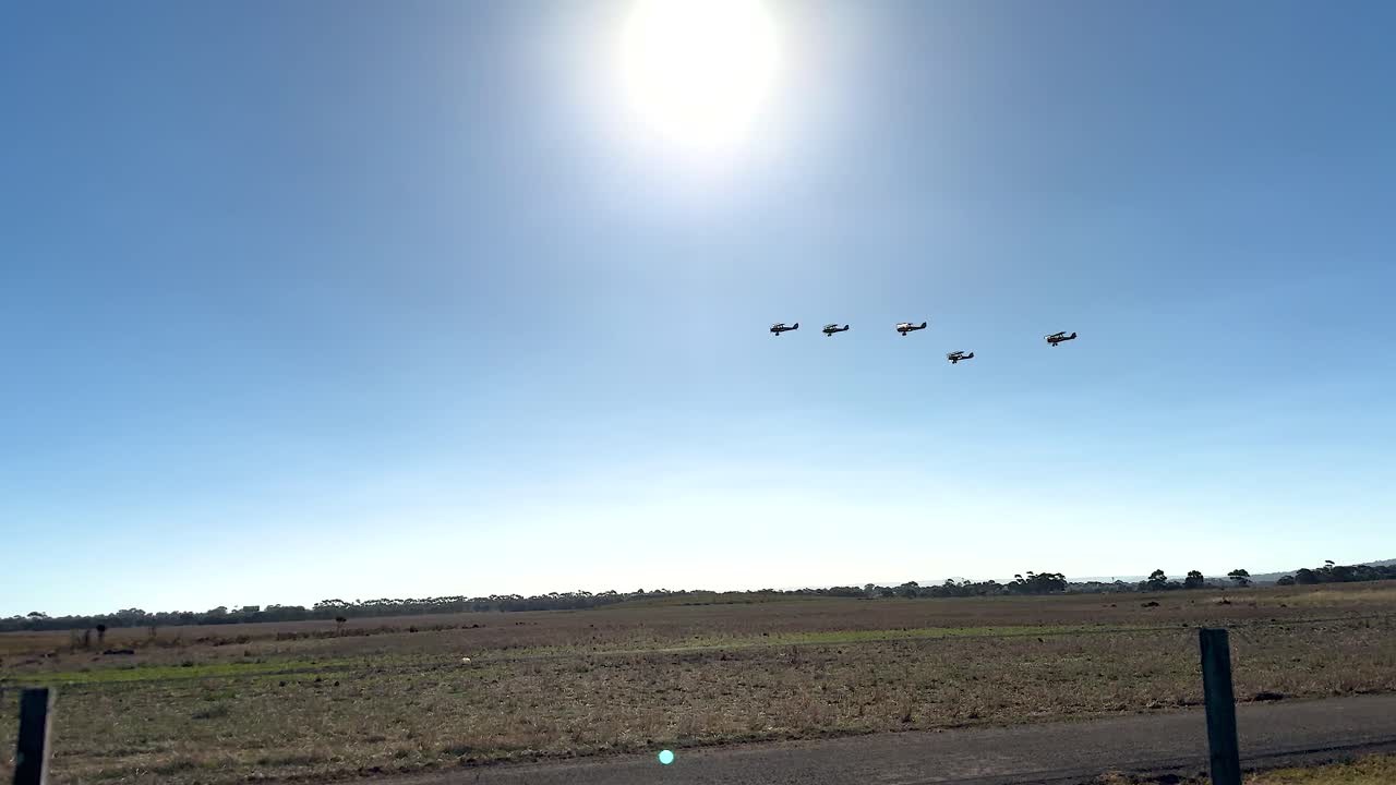 Vintage Biplanes in Formation Flight Over Rural Landscape