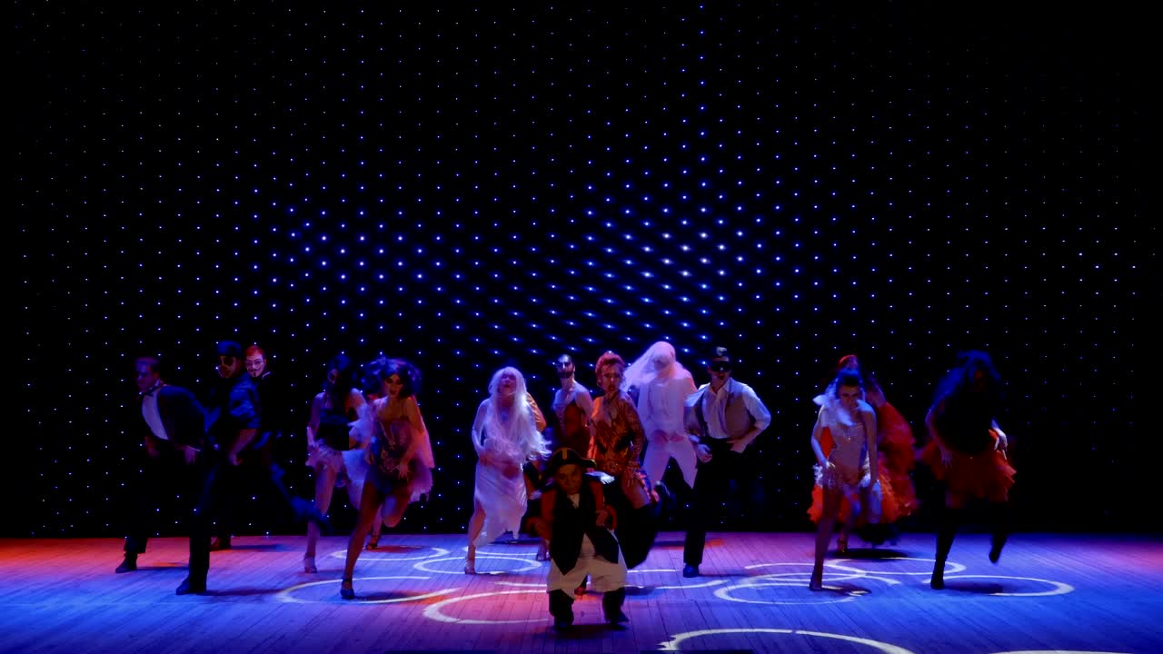 장면적인 의상을 입은 예술가들이 극장에서 무대에서 춤을 추고 있습니다.