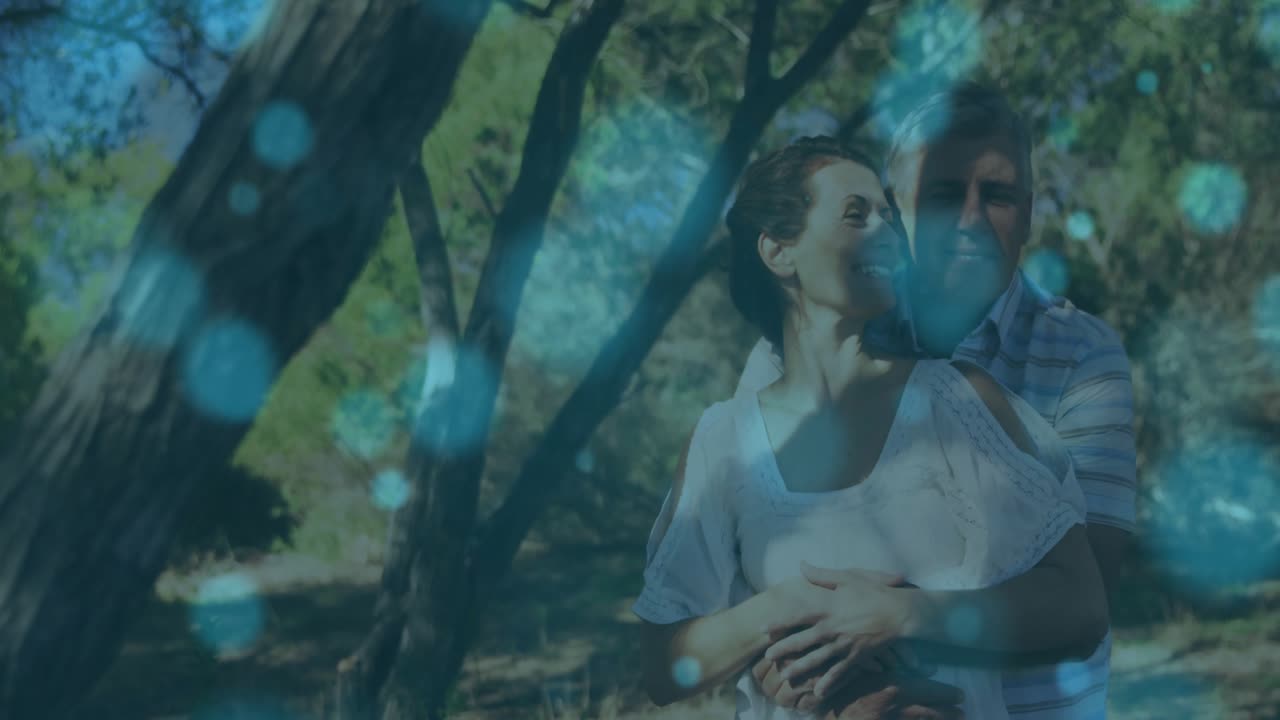 Casal alcançando um galho, criando luzes bokeh azuis enquanto se abraçam, compartilhando laços para uma campanha de saúde