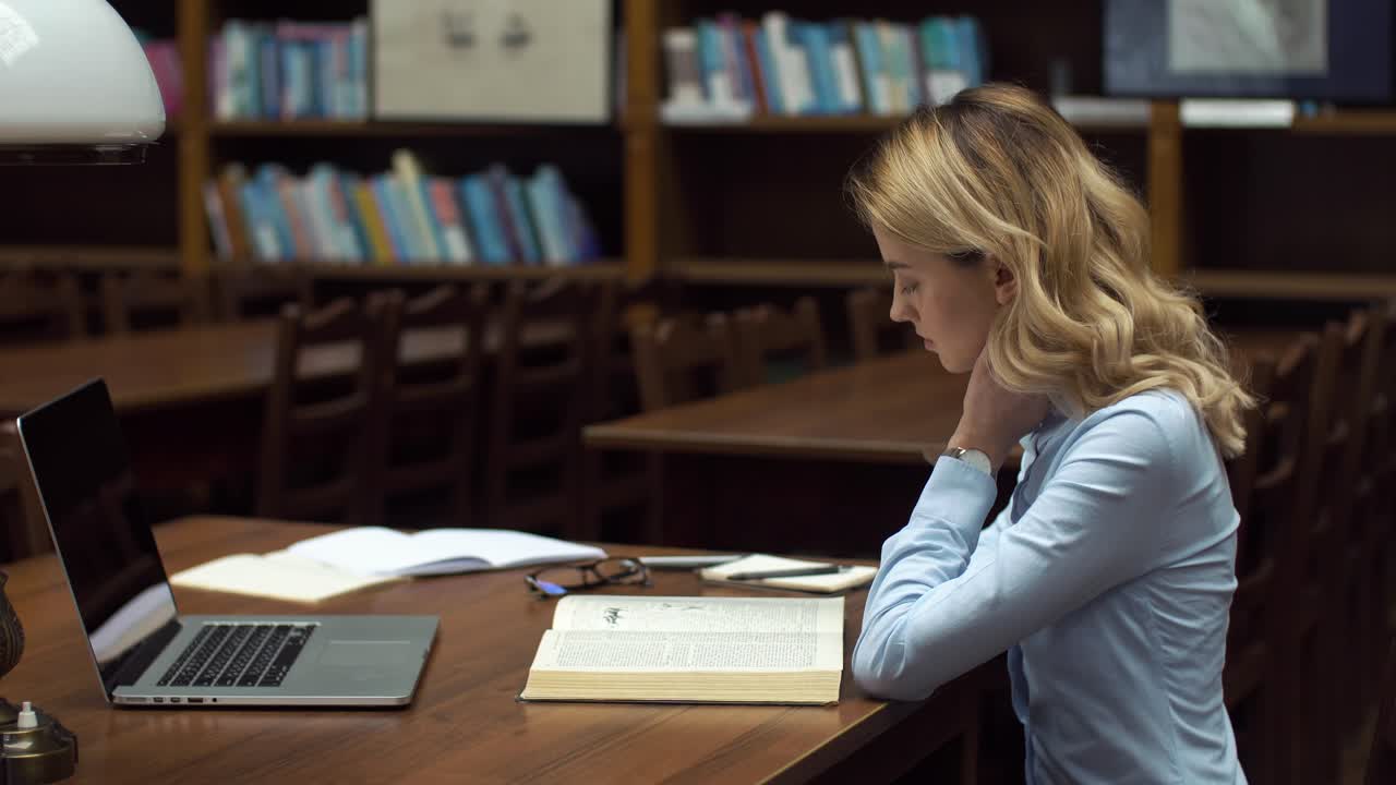 Woman Studying in Library with Laptop and Book