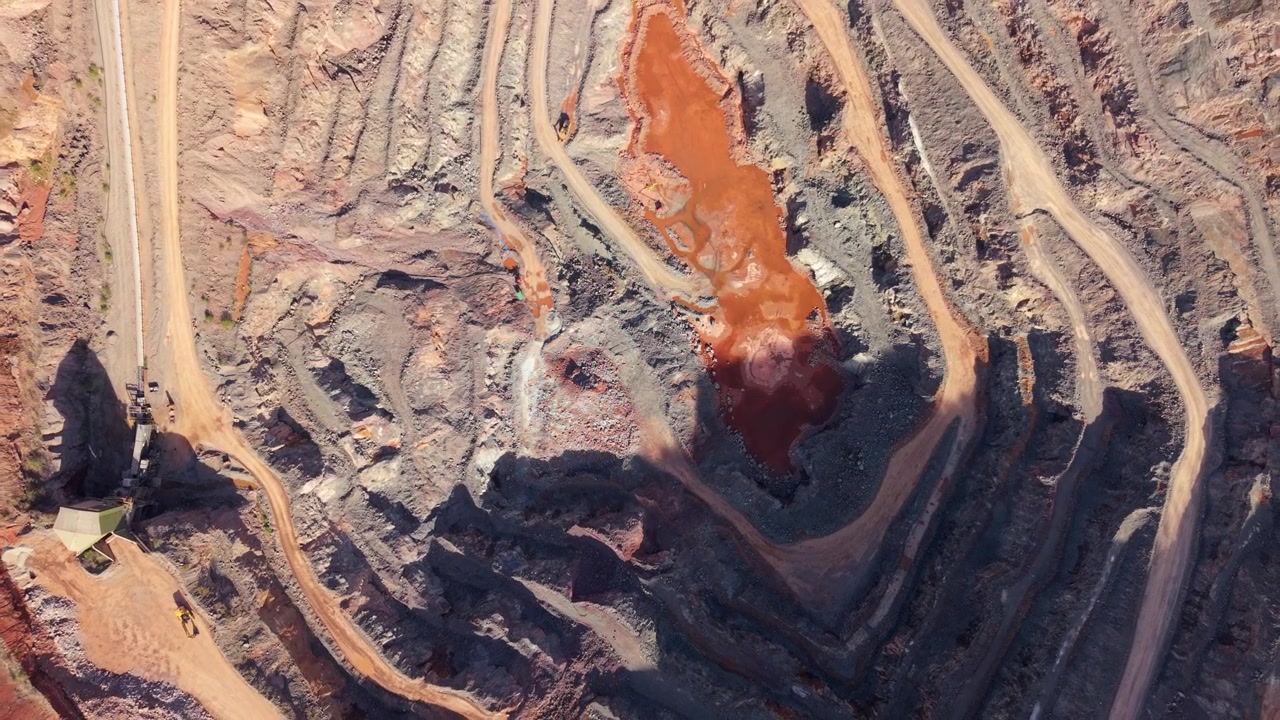 Drone Shot Over Deep Open-Pit Mineral Quarry and Terraced Red Rock Benches