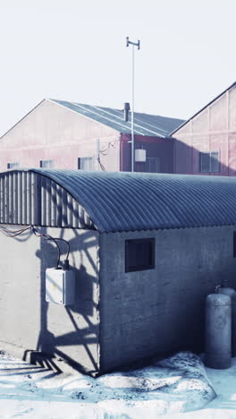 a concrete building with a metal roof in a snowy industrial area