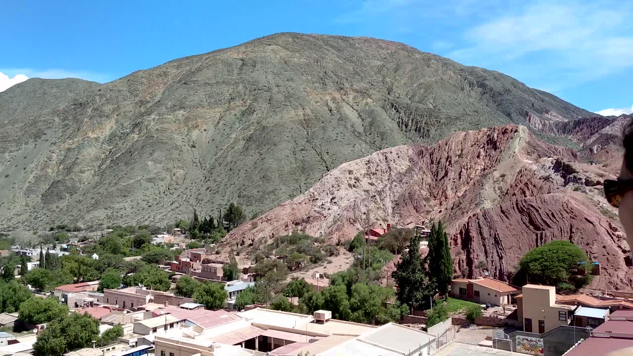 una mujer joven tomando fotos con vistas a la ciudad de purmamarca, argentina