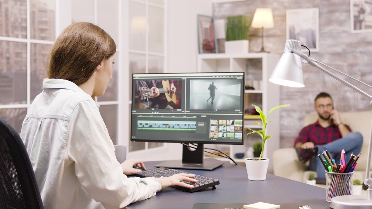 Mujer joven editando video en la computadora en su oficina en casa