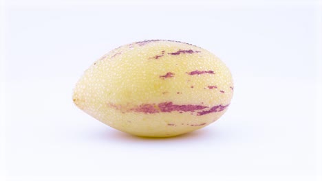 one whole mature yellow pepino with water drops. rotating on the turntable. isolated on the white background. close-up. macro.