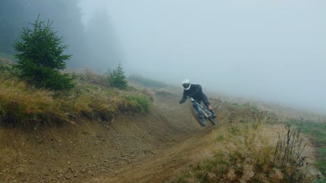 a mountain biker rides an alpine trail covered in fog