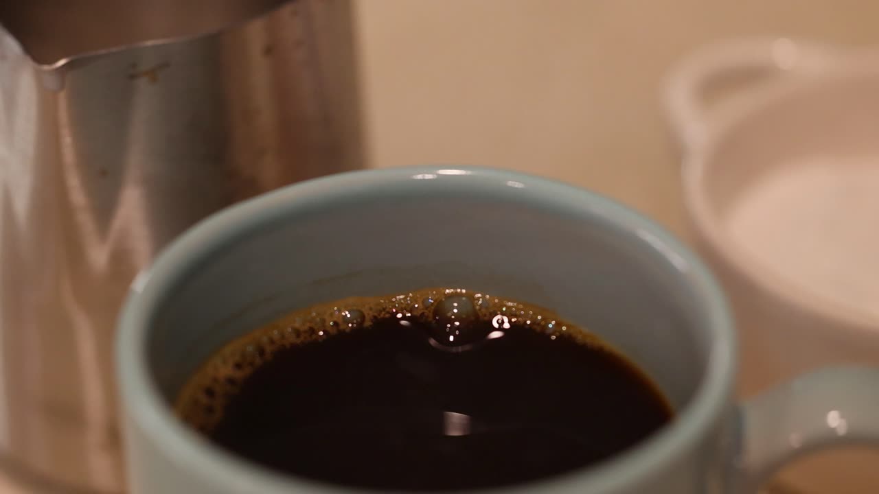 A spoonful of sugar is added to a steaming cup of coffee, creating a warm and inviting atmosphere