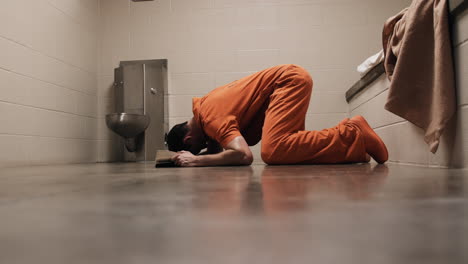 A-religious-prisoner-in-prison-cell-falls-on-knees-praying,-pray,-prayer,-crying,-cry