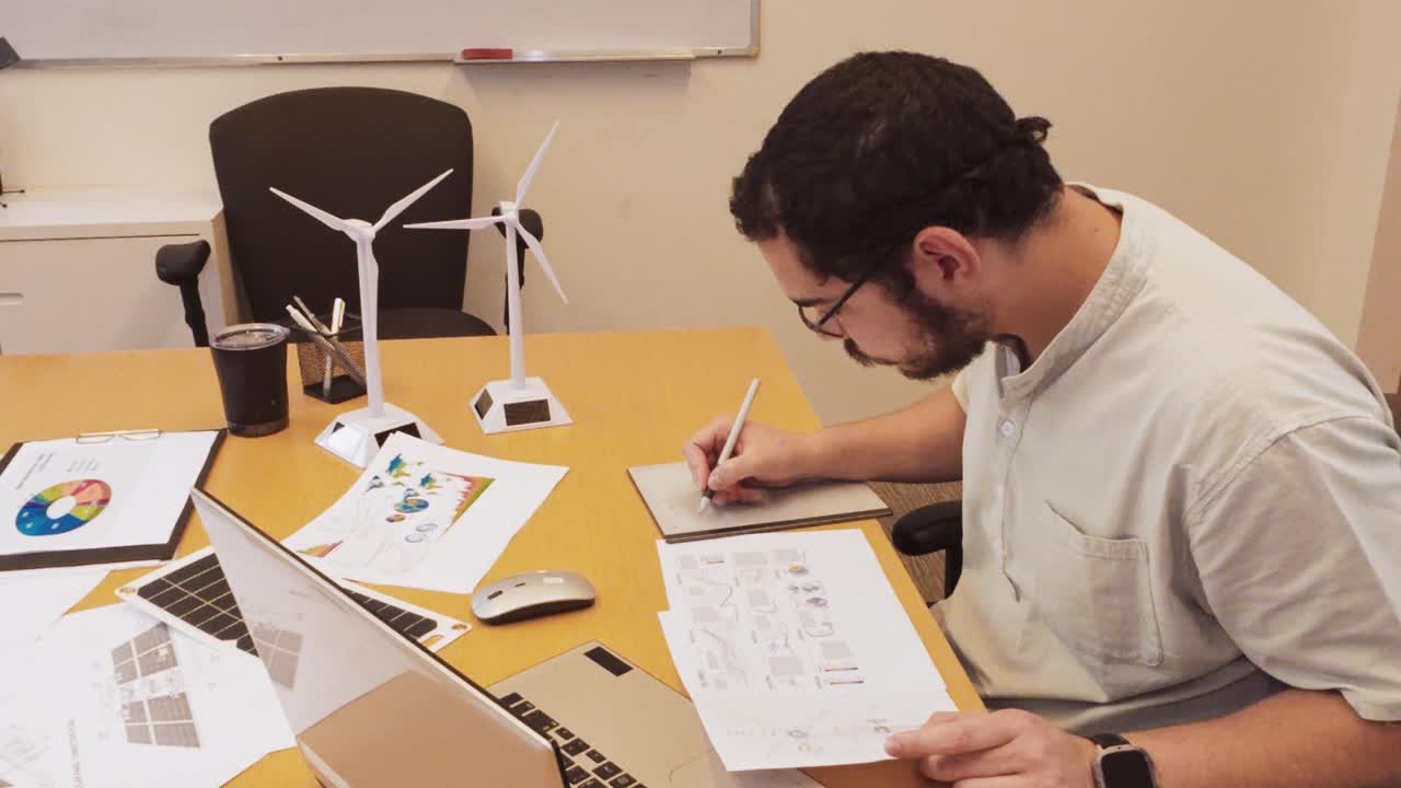 Man working on renewable energy project with wind turbine models